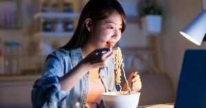 Craving Comfort Food? Discover the Best Instant Ramen 1 (woman eating ramen at her computer)