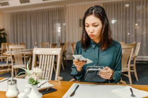 The Price of Flavor: How Much Is a Bowl of Pho Worth? 1 (woman reading the bill at a restaurant)