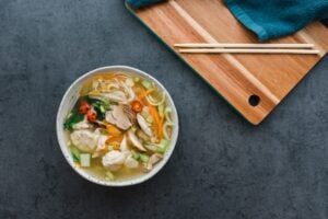 How Many Calories Are in a Large Bowl of Pho with Chicken? 2 Person eating noodle soup with chopsticks at desk indoors